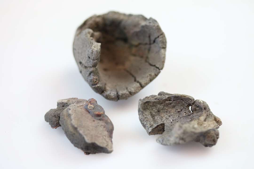 Dele til en digel og rester af yderlig en eller flere�den ene m�ler:�h�j 4,5 cm�diam. 3,5 cm�fastsmeltet slagge og rest af v�vning